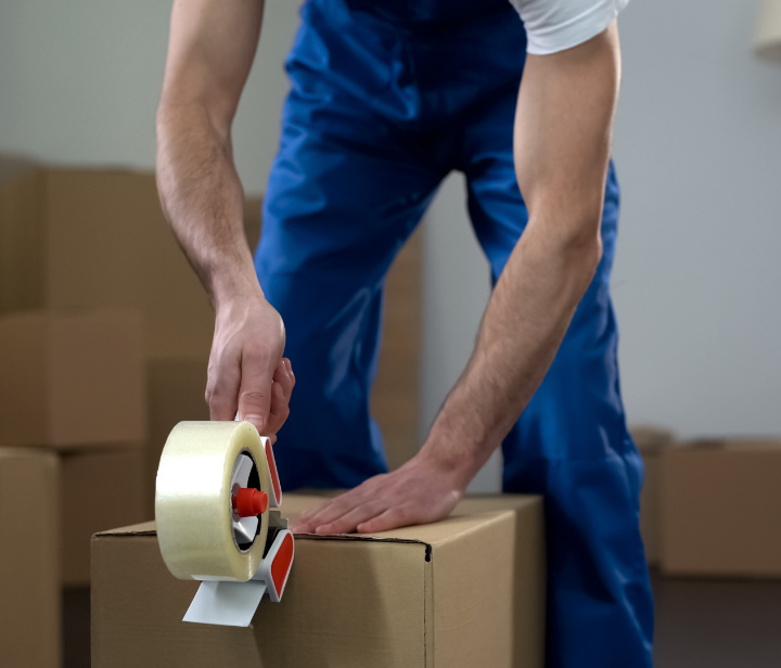 Moving company worker packing cardboard boxes, quality delivery services